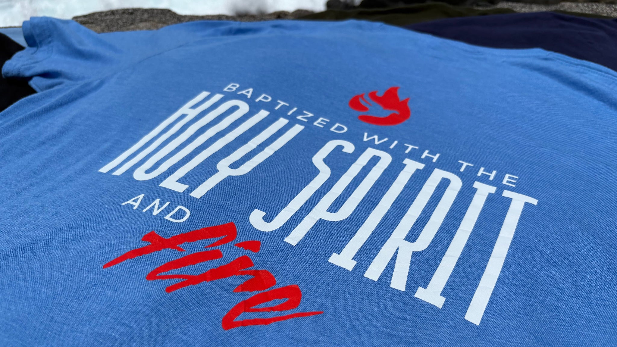Blue t-shirt with text and red graphic design on a beach background